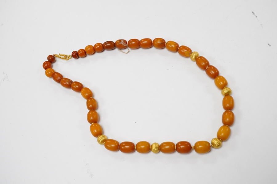 An amber and gold necklace, composed of amber beads measuring approximately 0.6 - 1.1cm, to a clasp and fluted spacer beads in gold, length 46cm, stamped 750, gross weight approximately 34 grams